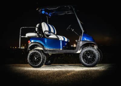 Blue golf cart with white and blue seats and blue led lights at night