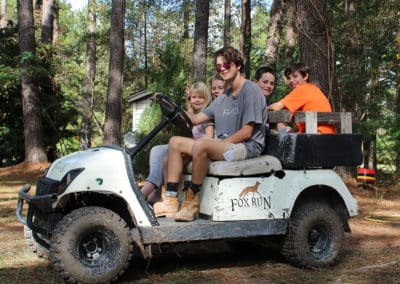 Kids having fun in a muddy custom golf cart labelled Fox Run
